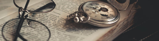 glasses and a pocket watch on top of a historical book